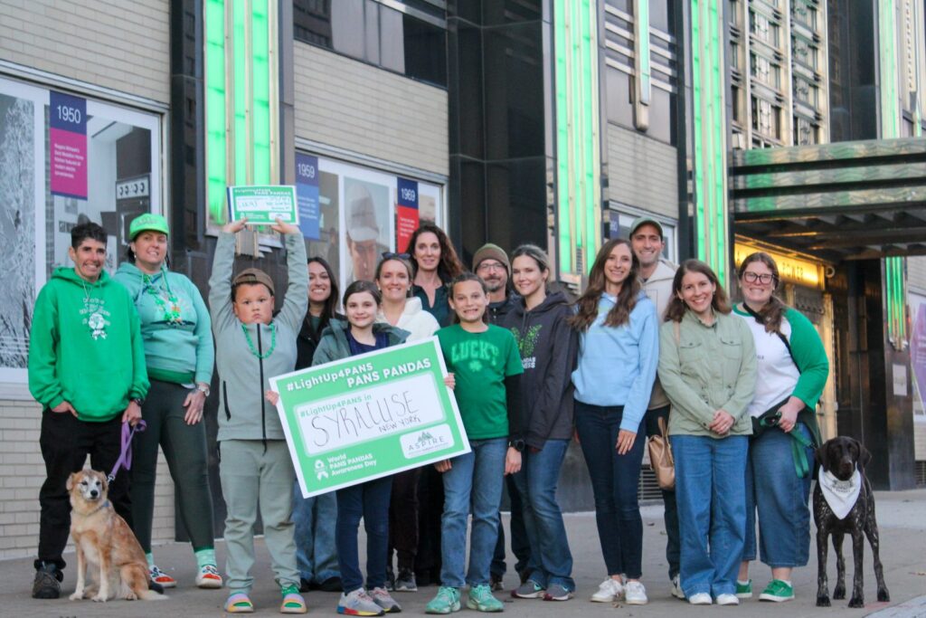 Families and supporters dressed in green gather outside the National Grid Building in Syracuse on Awareness Day 2025