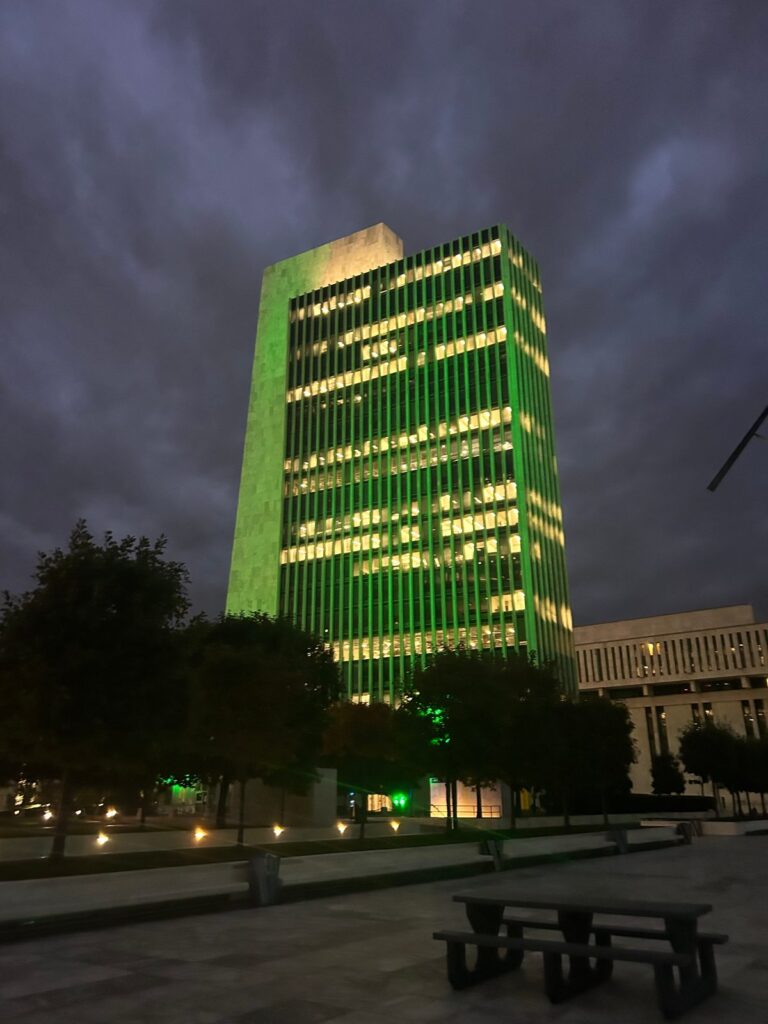 A tower at Empire State Plaza in Albany lit green against a cloudy sky, October 9, 2026